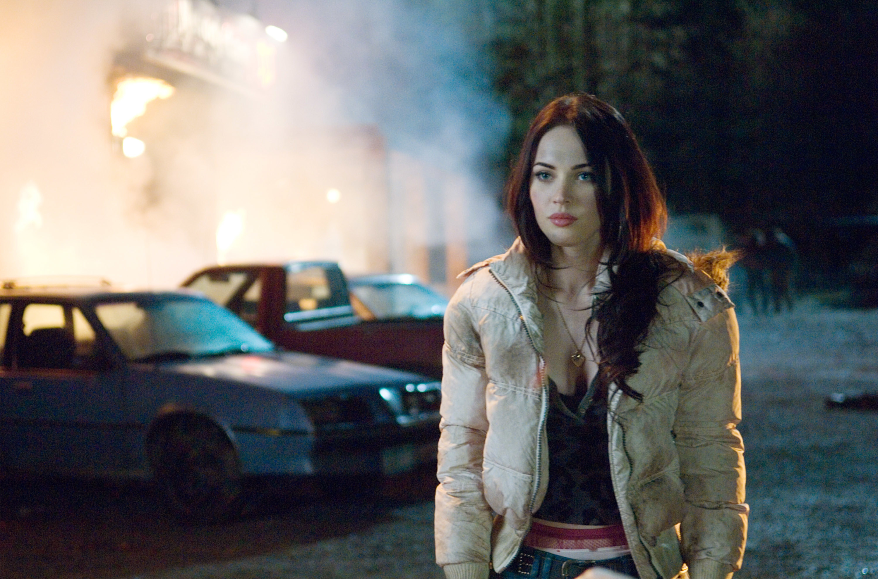 Megan Fox next to some burning cars