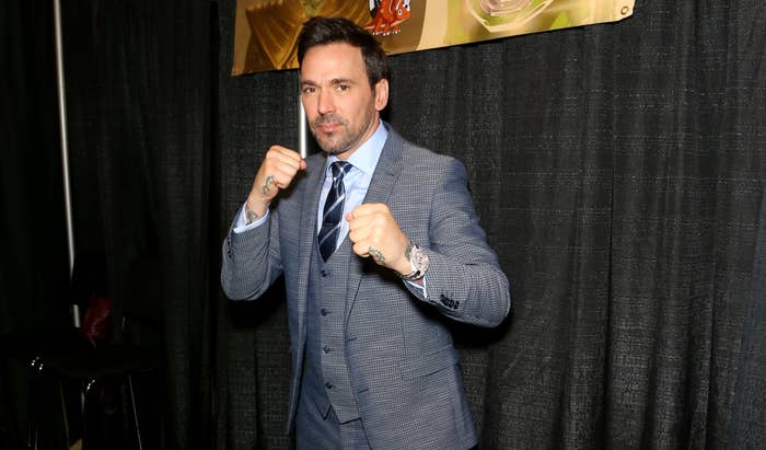 Jason in a three-piece suit and tie with his fists raised