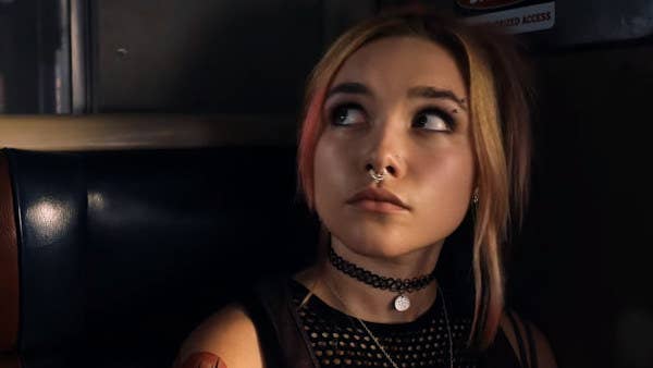 Florence Pugh with a nose ring sits on a train