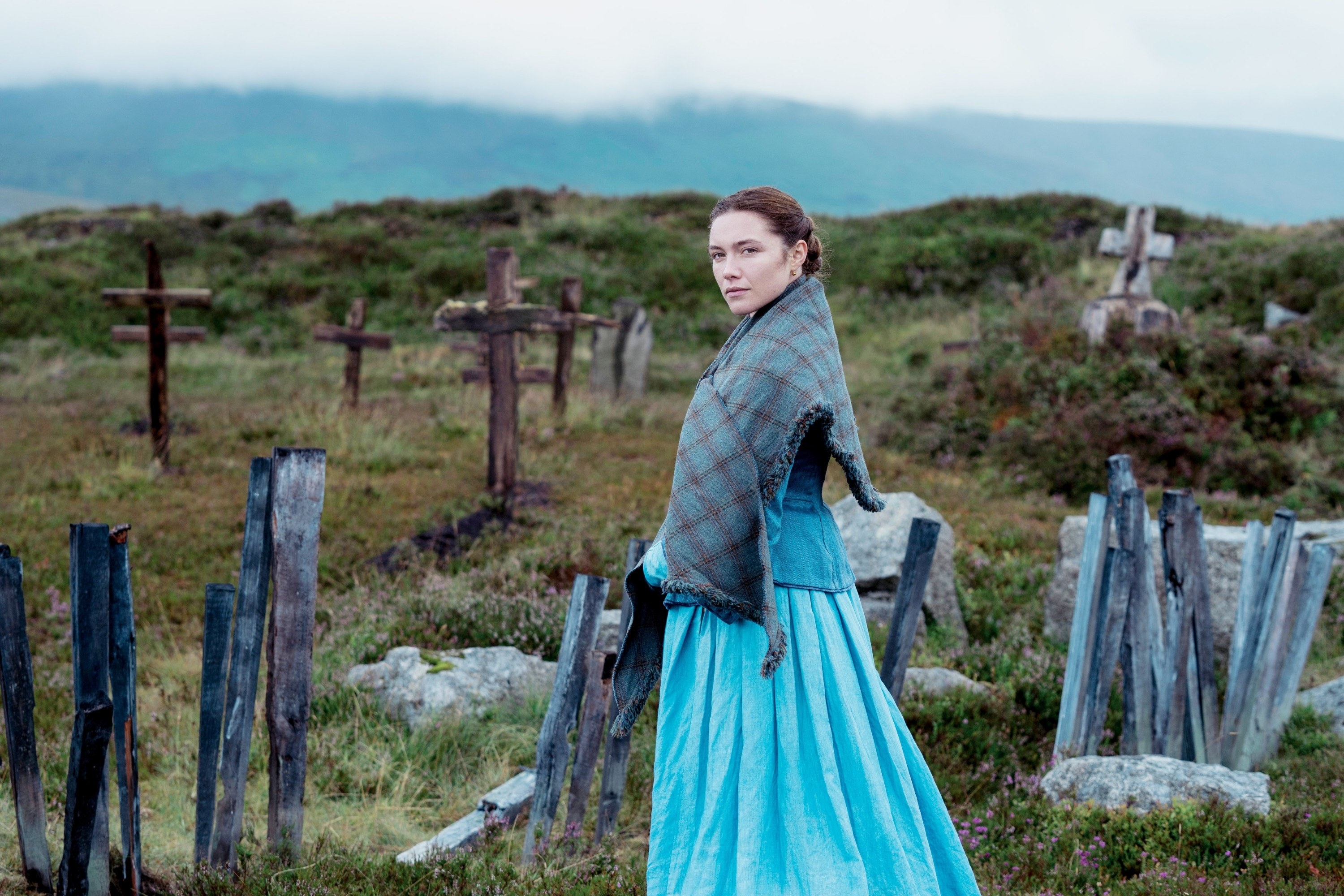 Florence Pugh wears blue and stands in a grave yard