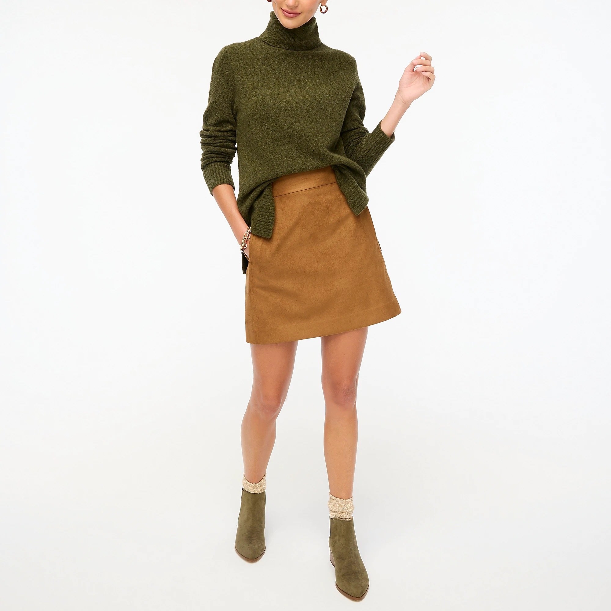 model in an olive green turtleneck sweater with side slits