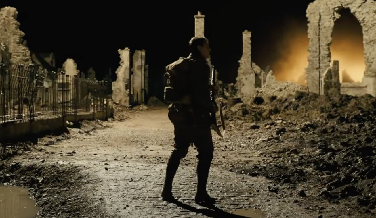 solider standing in the middle of a ruined town at night