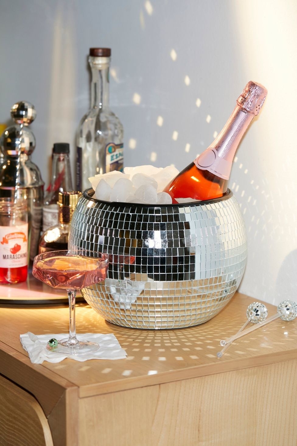 The round disco ball  bucket filled with ice and a bottle of champagne