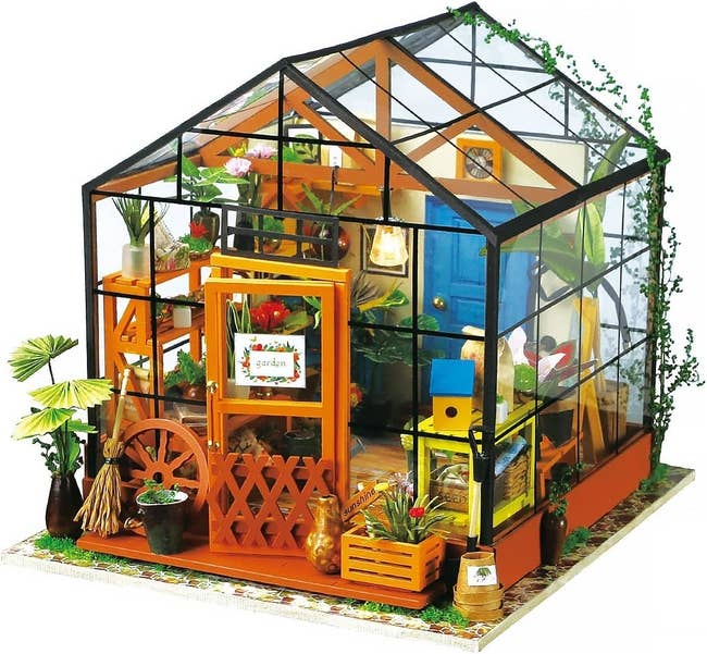 The completed miniature kit with plants, glasshouse exterior, shelves, furniture, and more