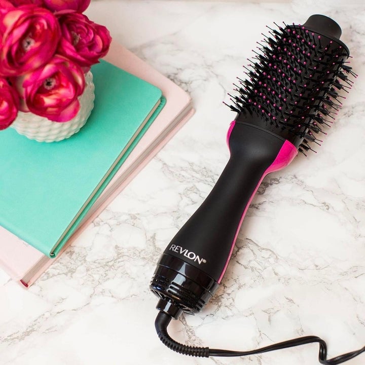 the brush on a table next to some books and flowers