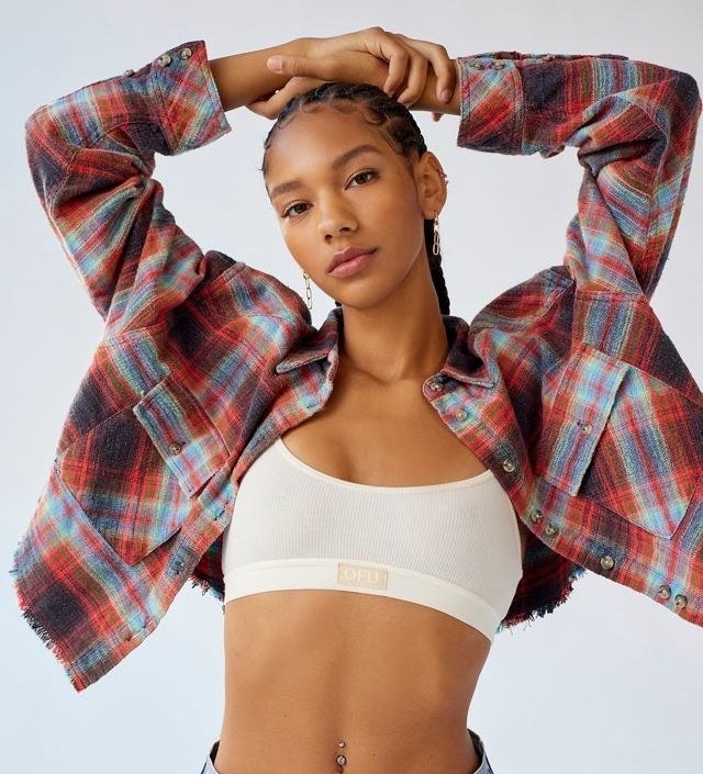 a person wearing the cropped flannel over a bralette