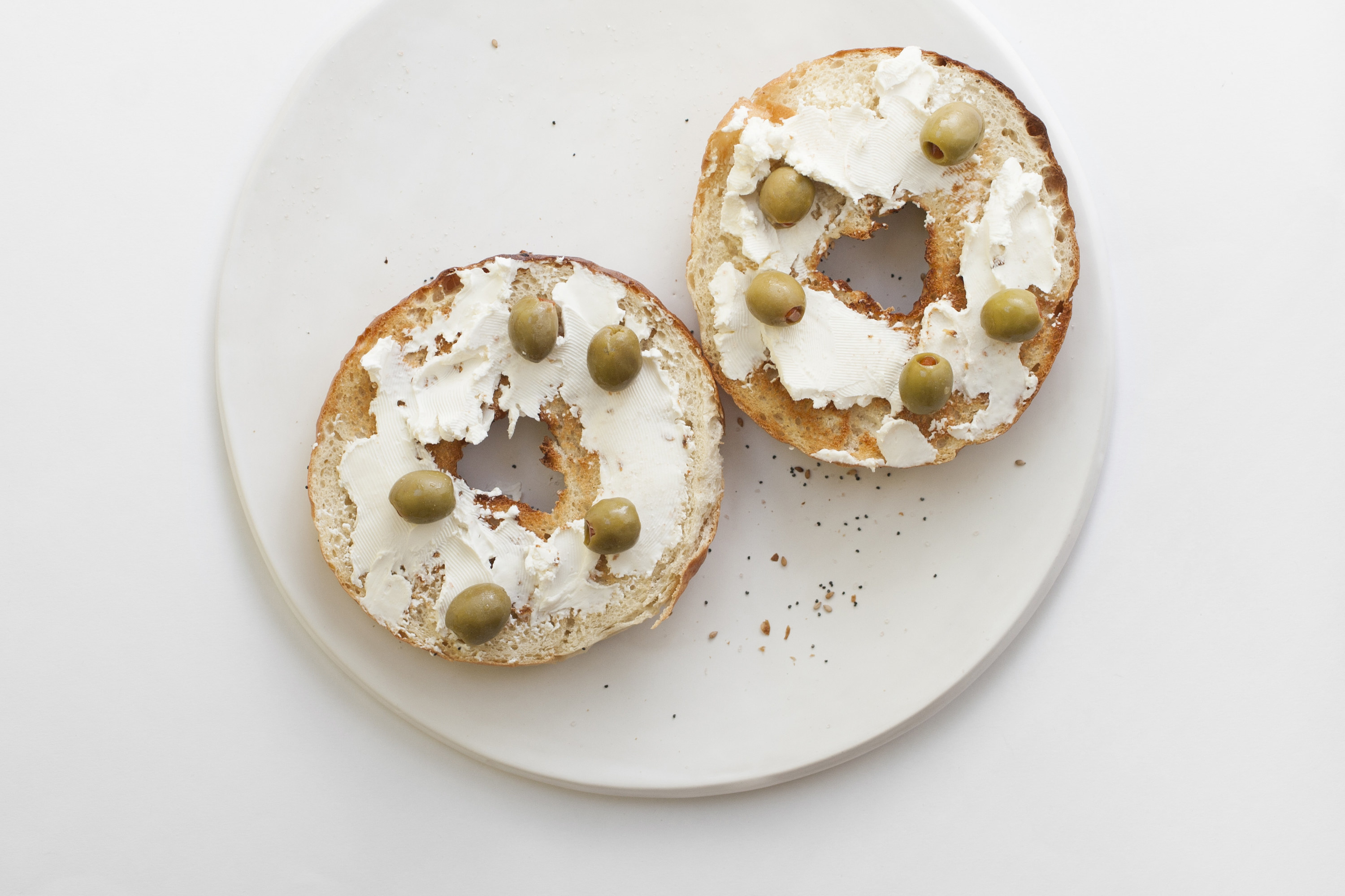 Green olives and cream cheese on a bagel.