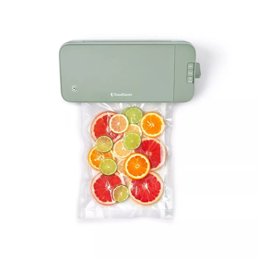 Green FoodSaver vacuum sealer sealing bag of citrus fruits