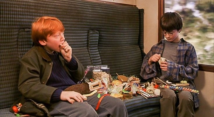 Rupert Grint and Daniel Radcliffe eat candy in a train car
