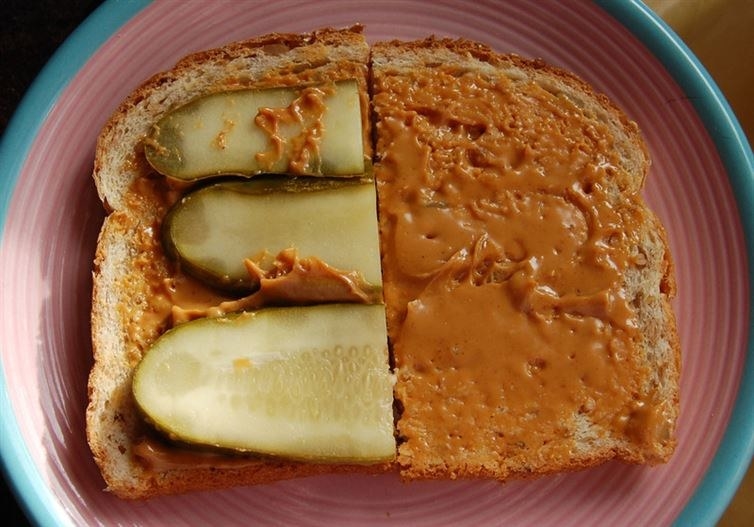A piece of bread topped with peanut butter and pickles.