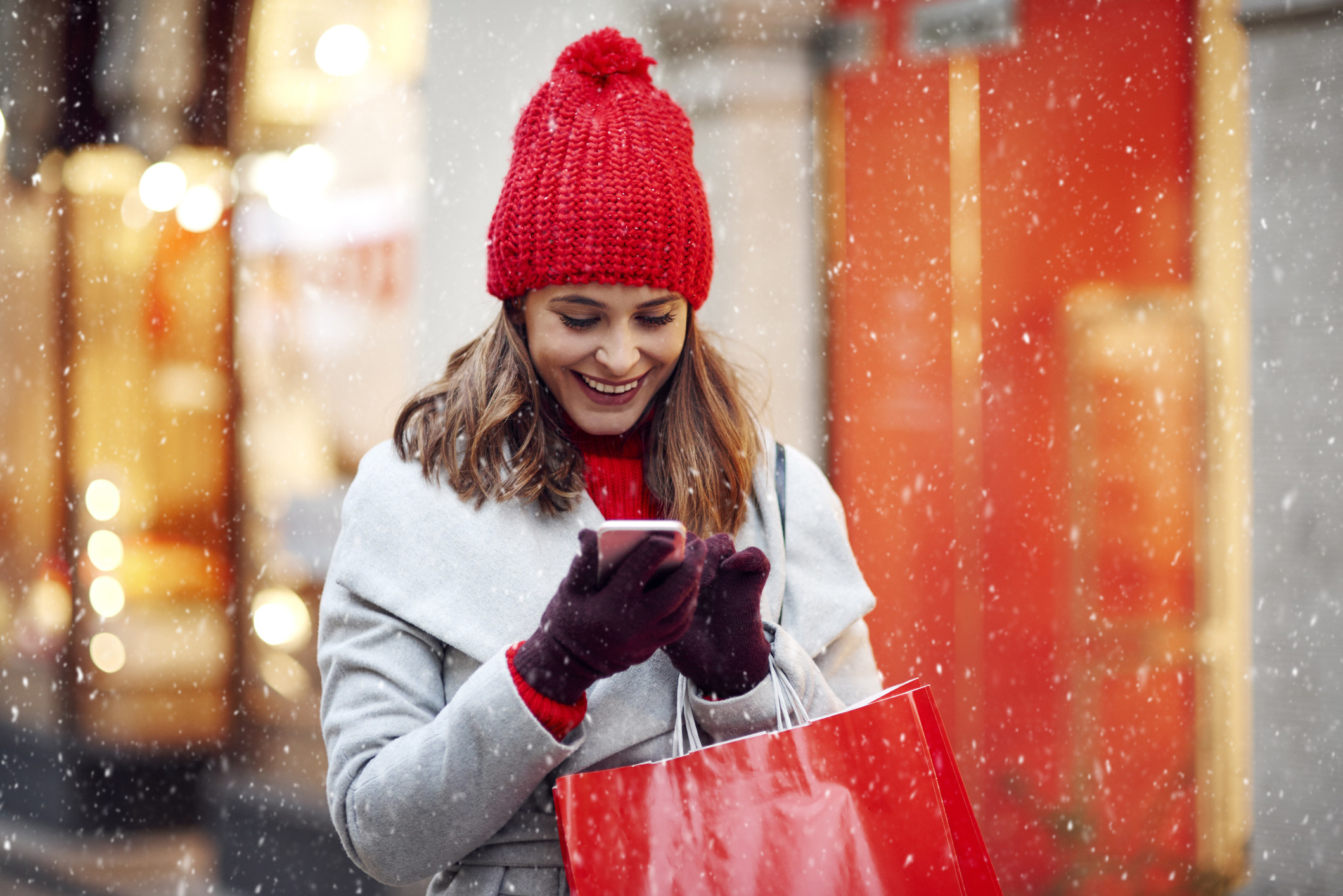 Woman smiling at her phone while shopping in winter