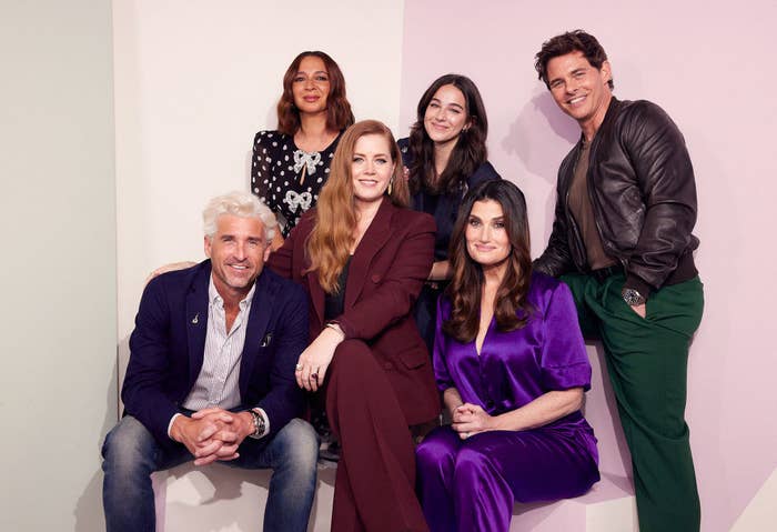 A promo photo of the cast of Disenchanted featuring from left to right sitting in the front: Patrick Dempsey, Amy Adams, Idina Menzel and Maya Rudolph, Gabriella Baldacchino, and James Marsden standing in the back