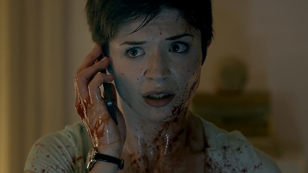 A terrified woman covered in blood answers her phone