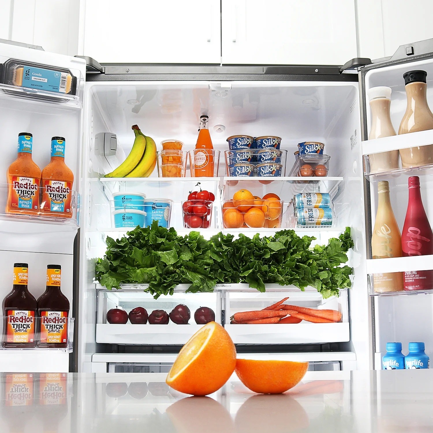 Clear fridge organizer bins with produce on fridge shelves