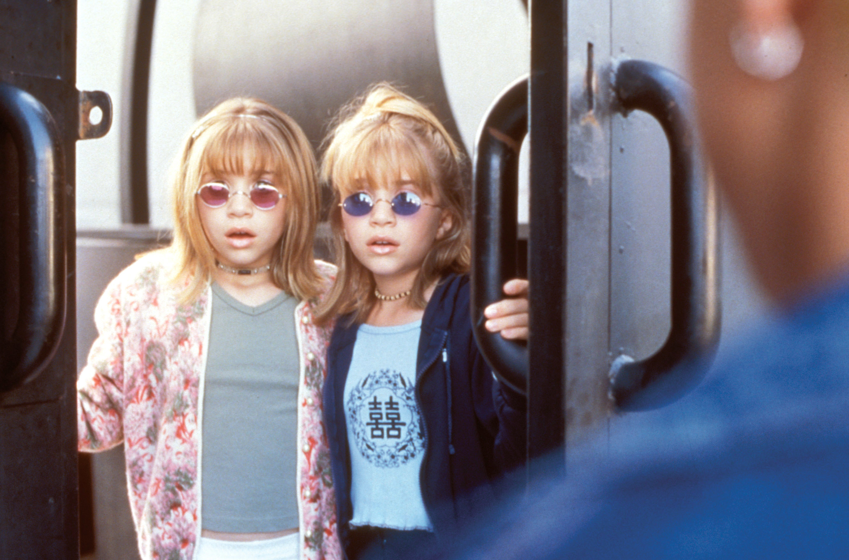 the Olsen twins wearing sunglasses, T-shirts, and jackets