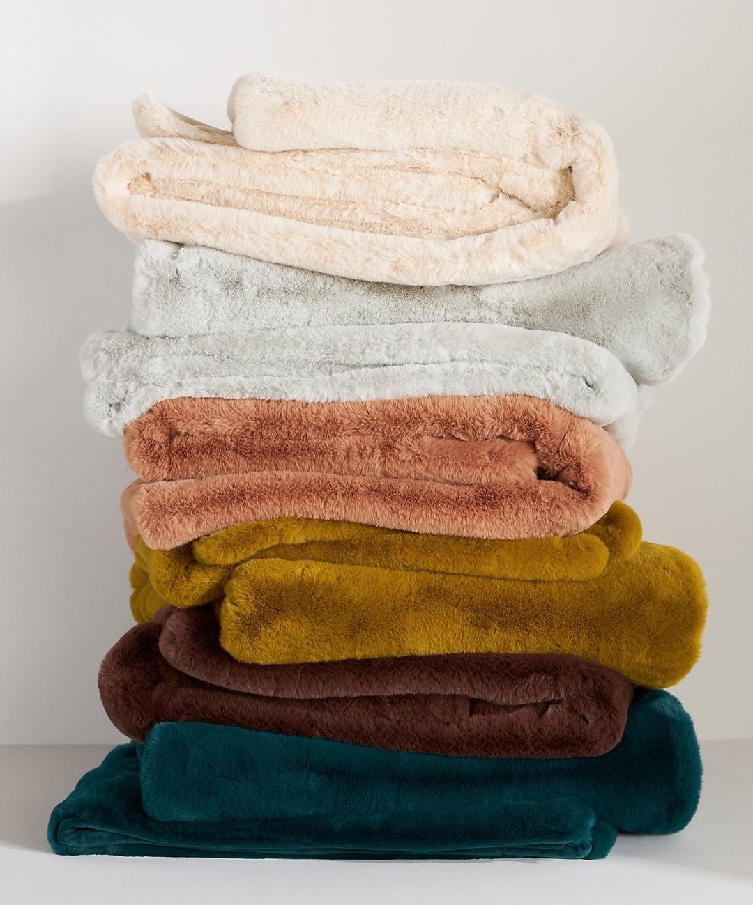 stack of folded faux fur blankets in jewel tones and neutrals