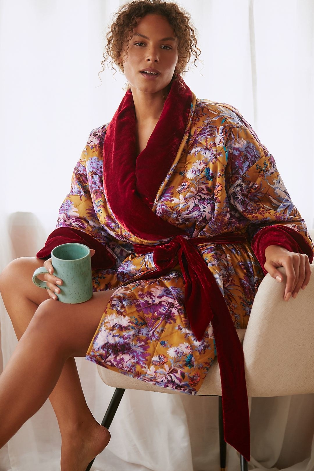 model in a short orange floral robe with red velvety trim and tie