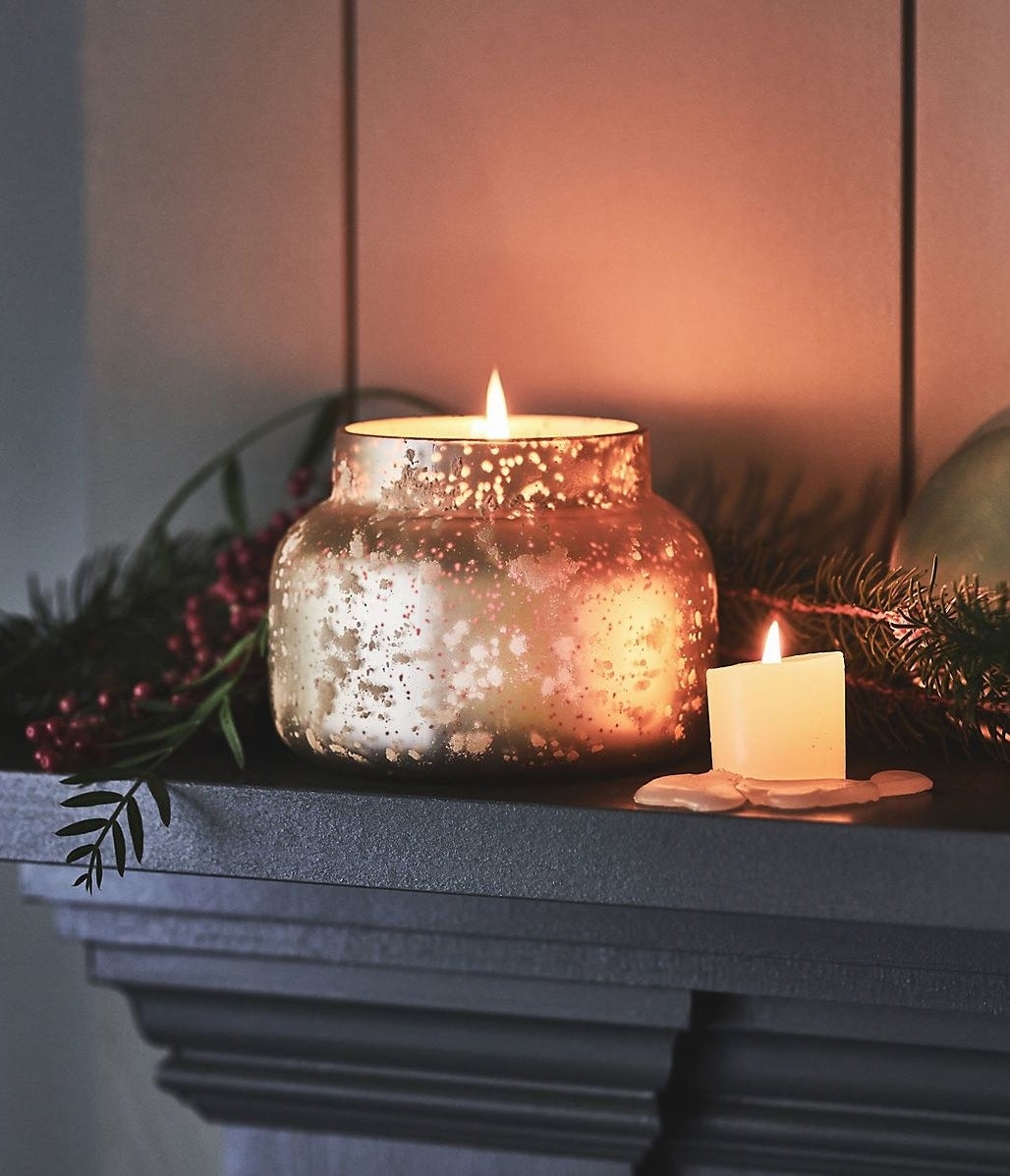 lit candle in a dappled gold jar on a mantle