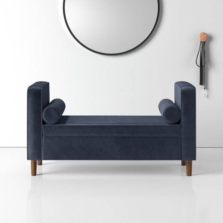 a dark blue bench with cylindrical matching pillows