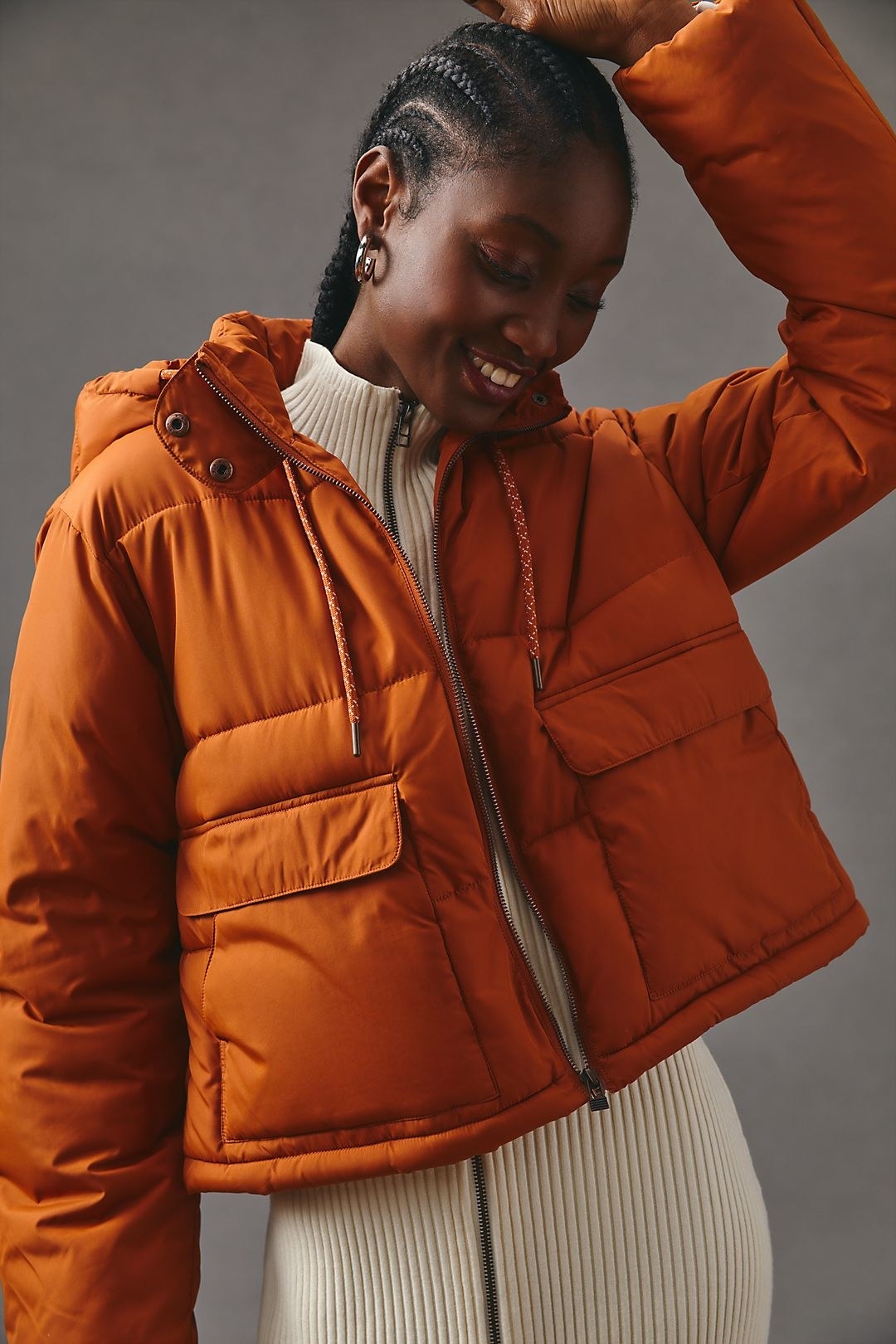 model in an orange cropped boxy puffer jacket with a hood and large pockets