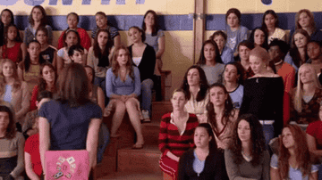Everyone raising their hands while sitting on gymnasium seats