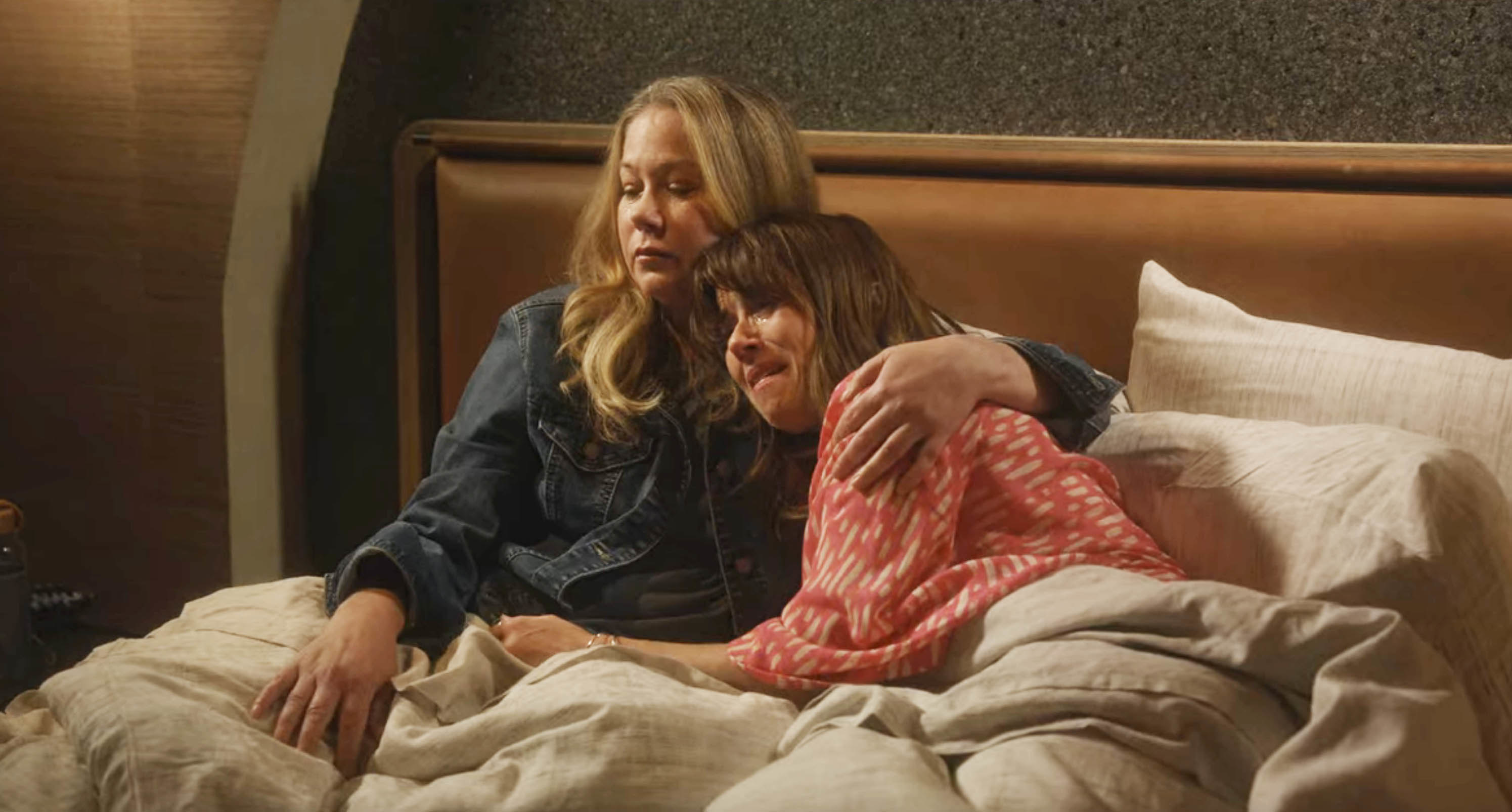 Jen and Judy sitting up in bed together and hugging