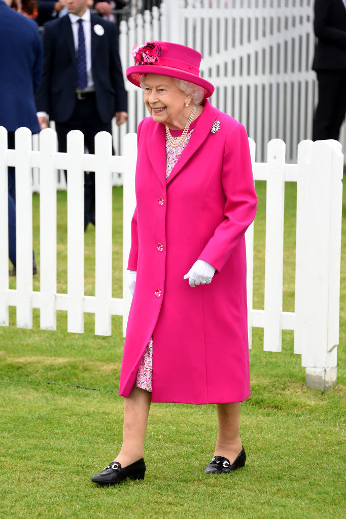 the queen walking on grass during an event
