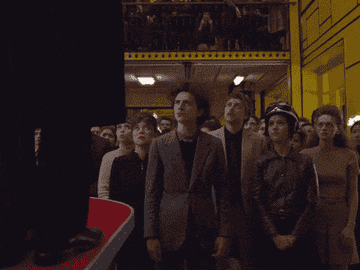 gif of timothee chalamet in the french dispatch leading a crowd in applause