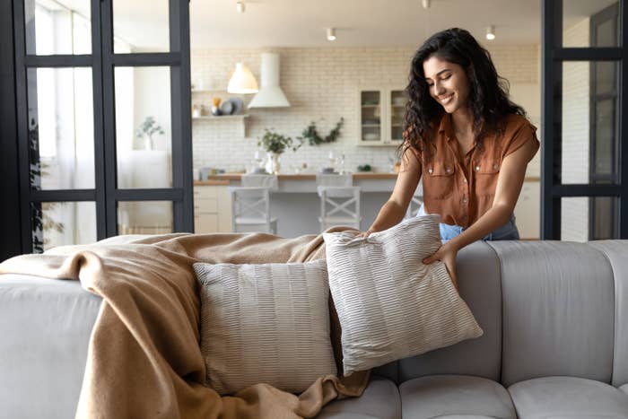 woman arranging pillows on her sofa