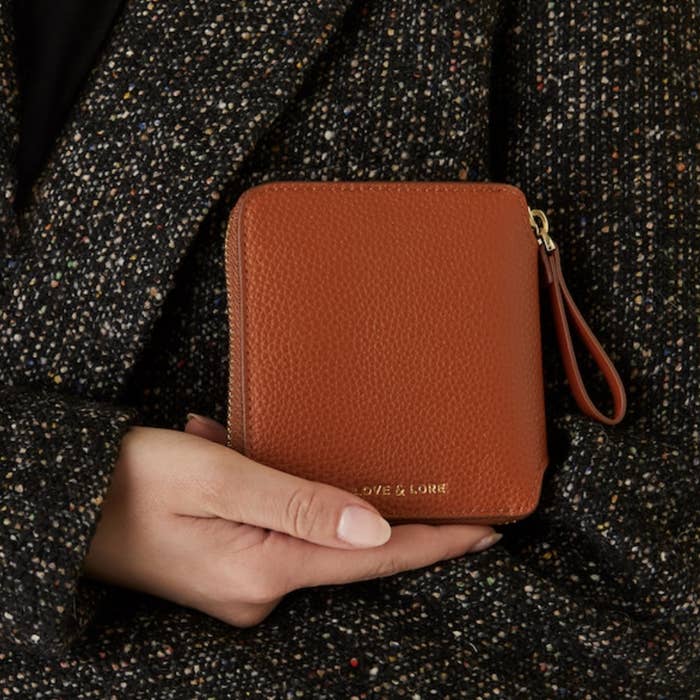 A person holding the wallet in front of their coat