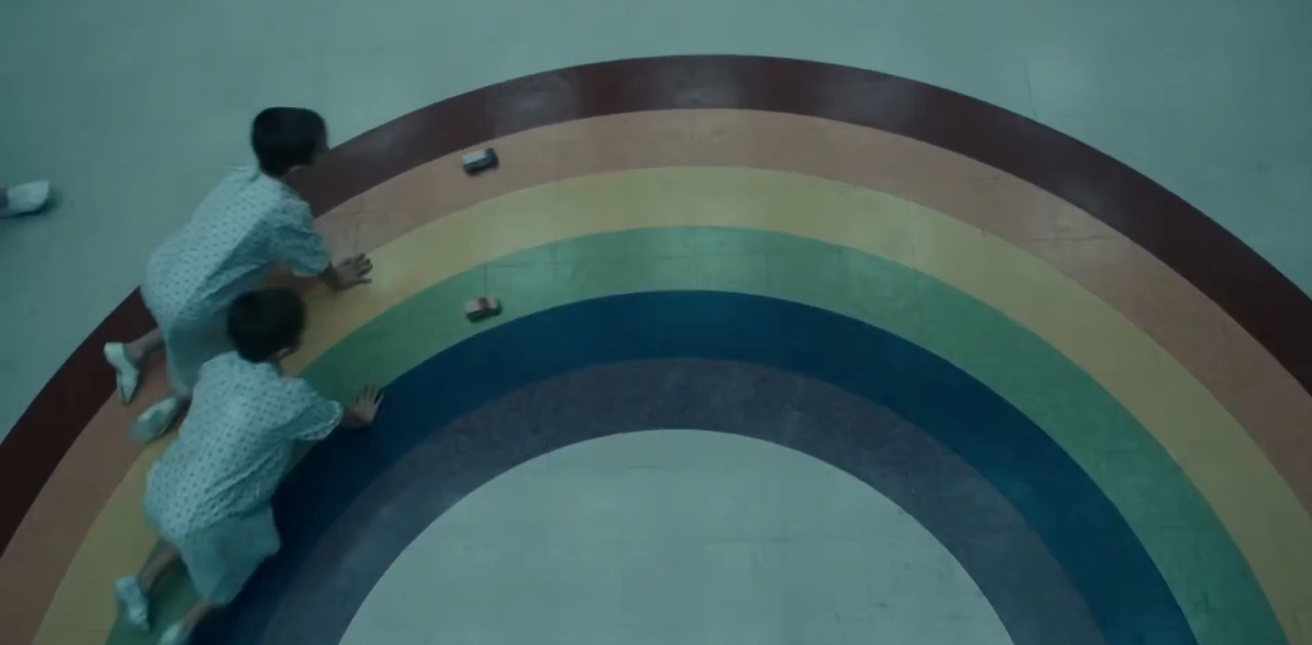 test subjects racing toy cars in a rainbow track