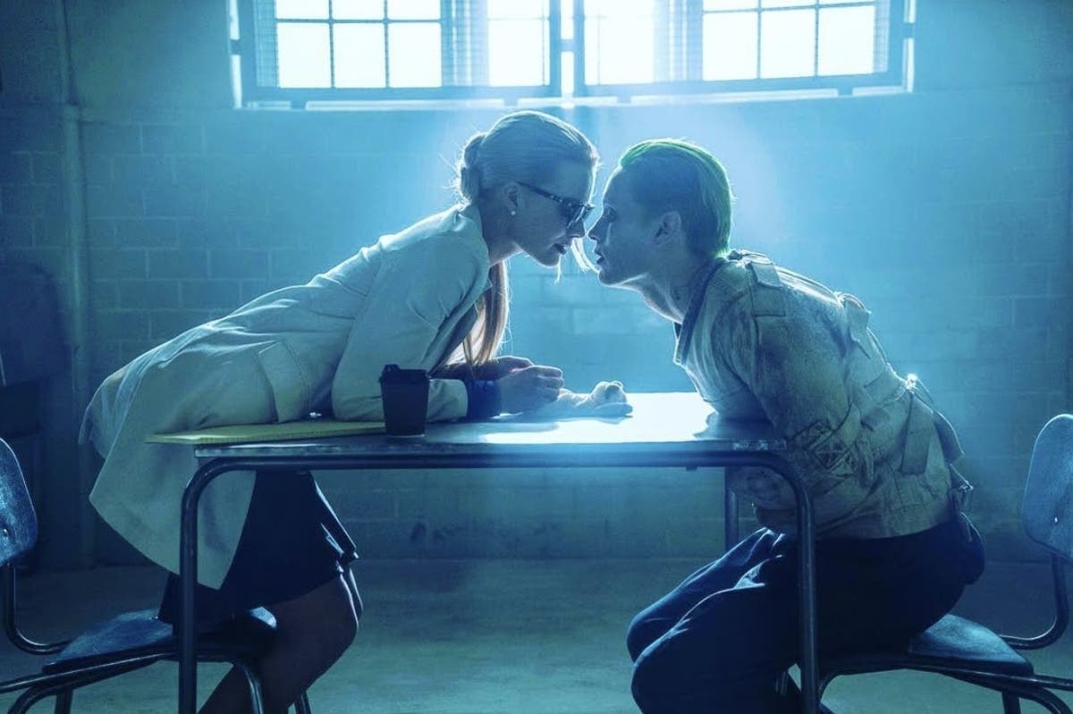 Margot Robbie leaning over a table towards Jared Leto