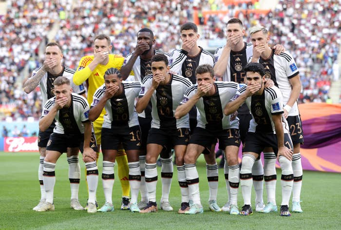 Germany players pose with their hands covering their mouths as they line up for the team photos on the field