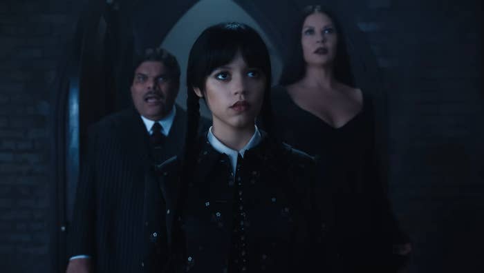 Wednesday Addams with her parents standing behind her