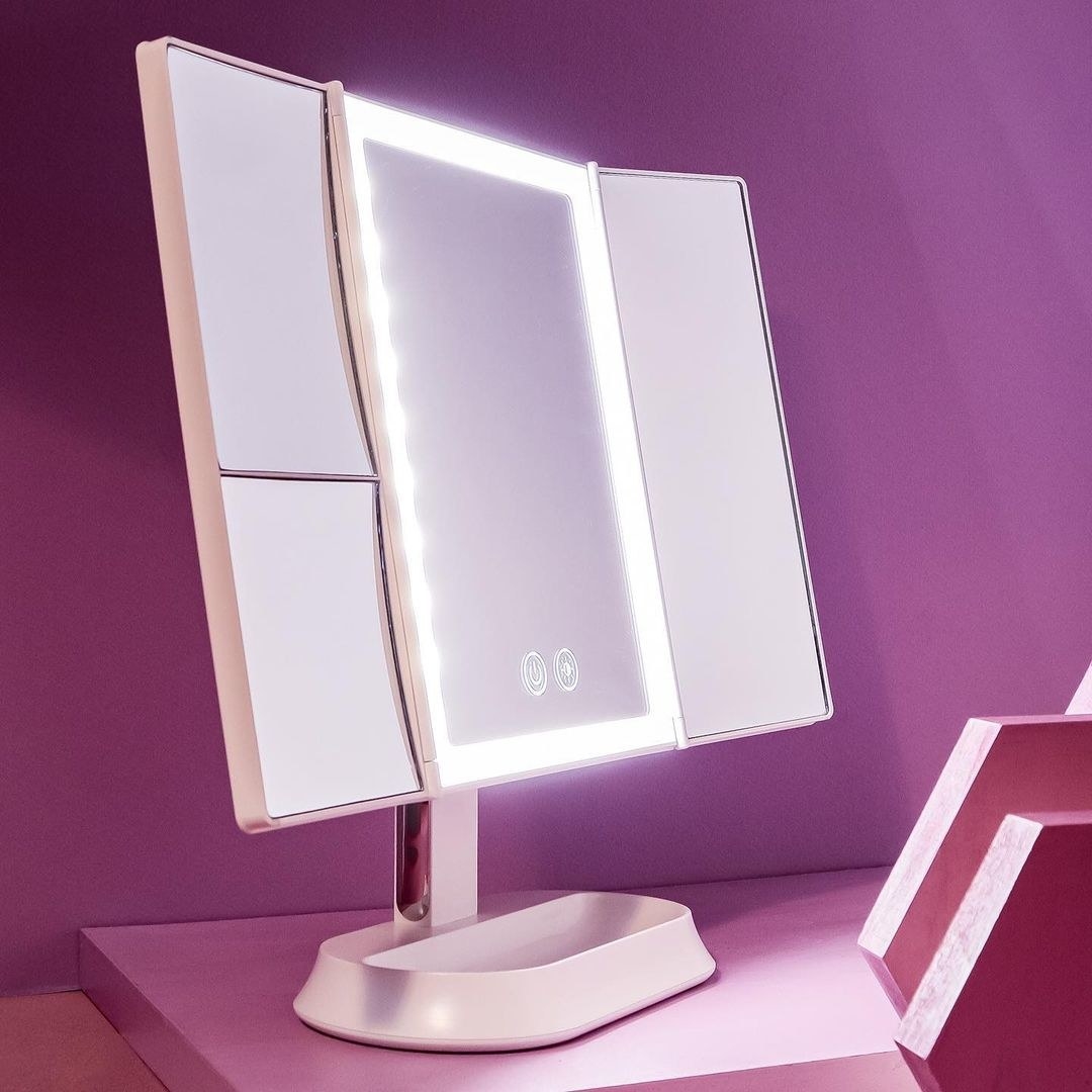 a trifold backlit vanity mirror with a trinket tray base
