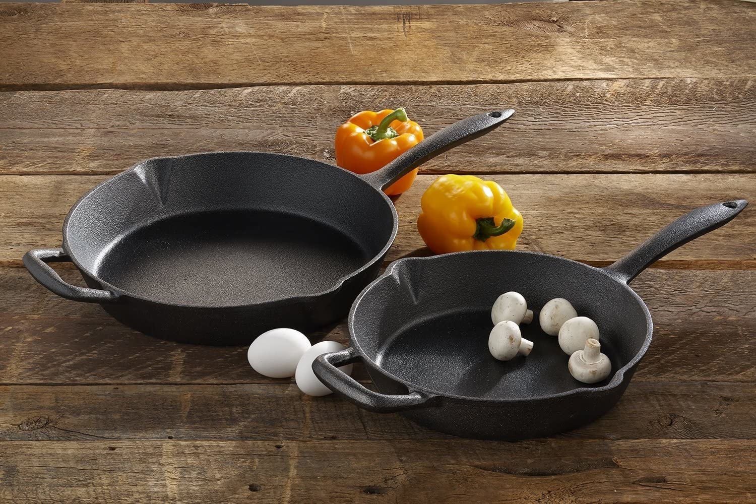 two cast iron pans on a wood surface