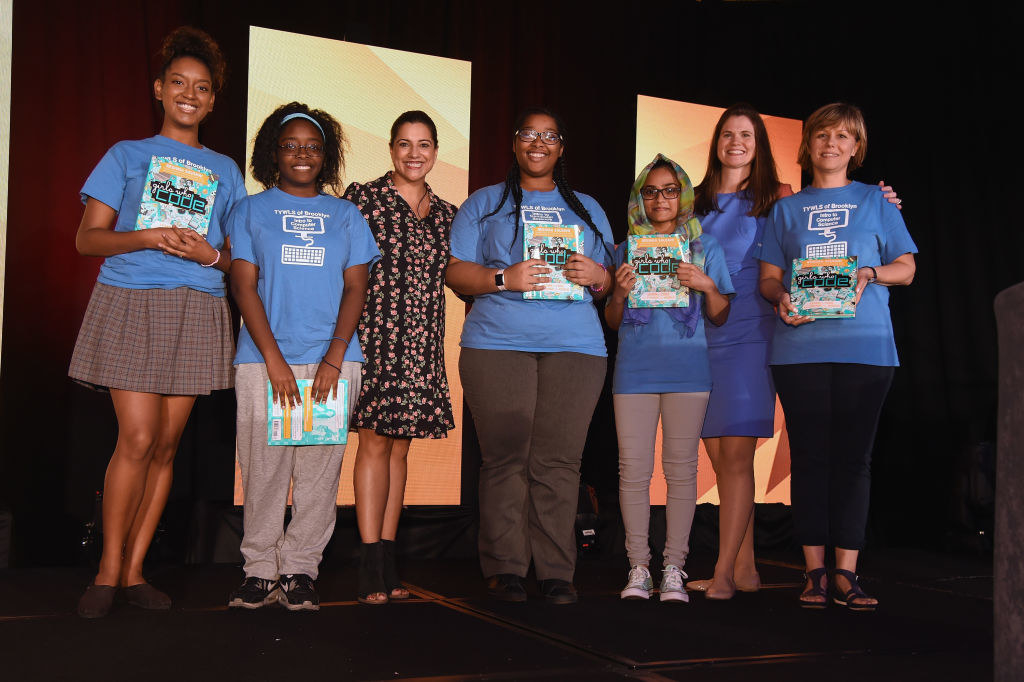 Reshma Saujani, black dress, poses for a photo onstage with Girls Who Code participants