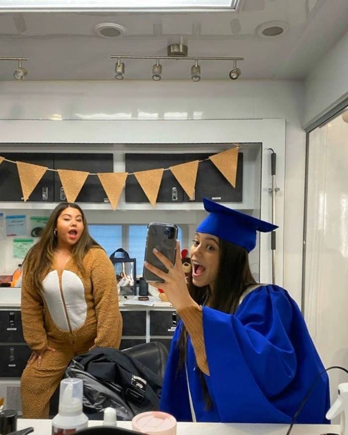 jenna ortega in graduation cap and gown with friend in background