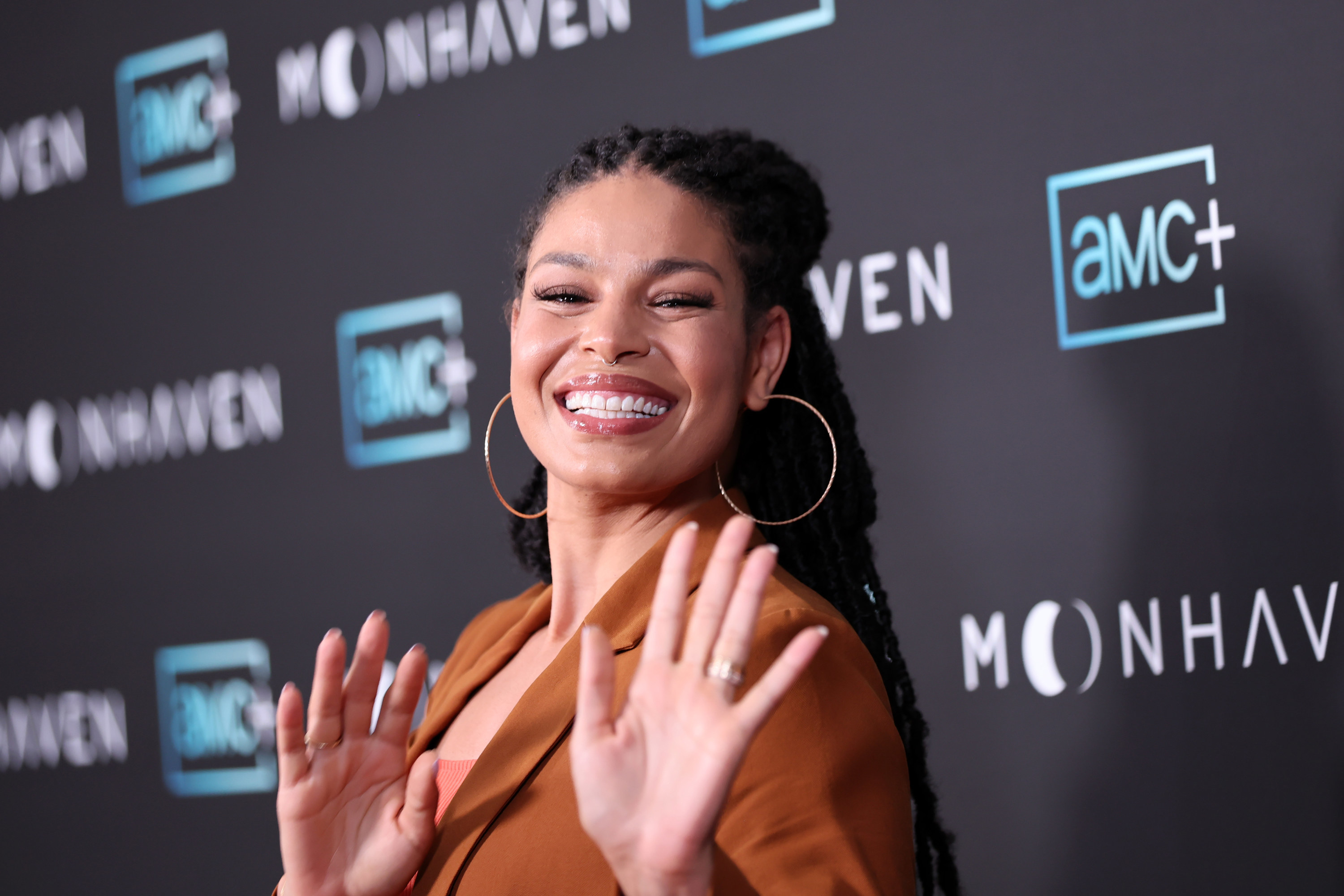 Jordin smiling widely as she waves at a red carpet event