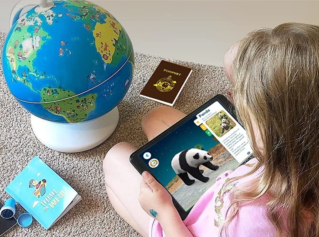 child using a tablet to learn about pandas with the globe in front
