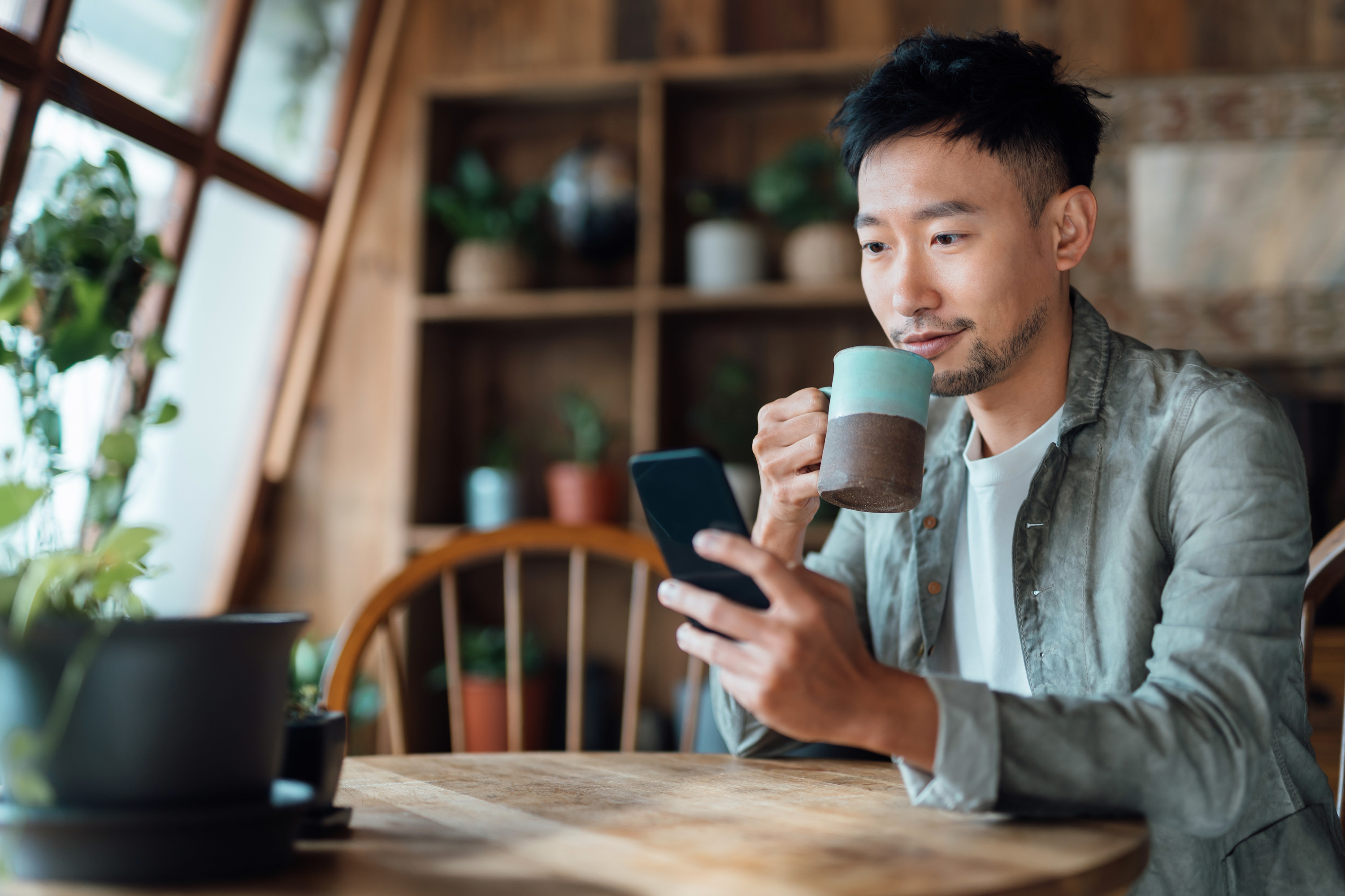 Man looking at his phone while drinking coffee