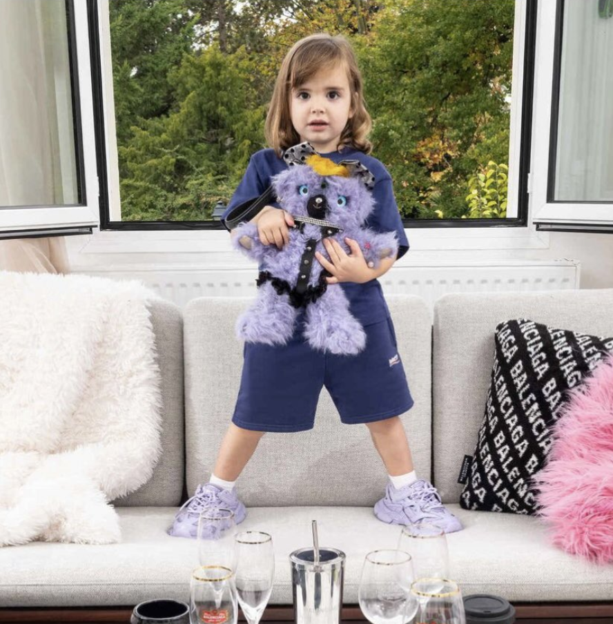 Balenciaga advertisement featuring a child holding a teddy bear in a BDSM-style harness