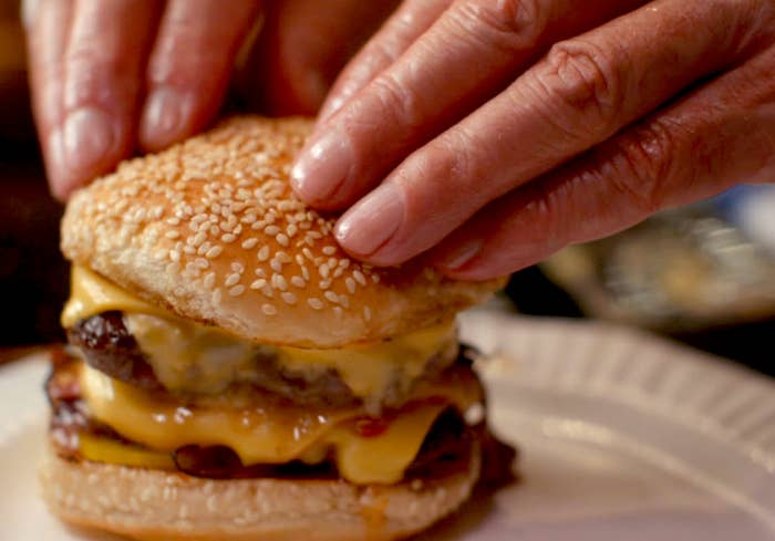 chef pressing down on cheeseburger in the menu
