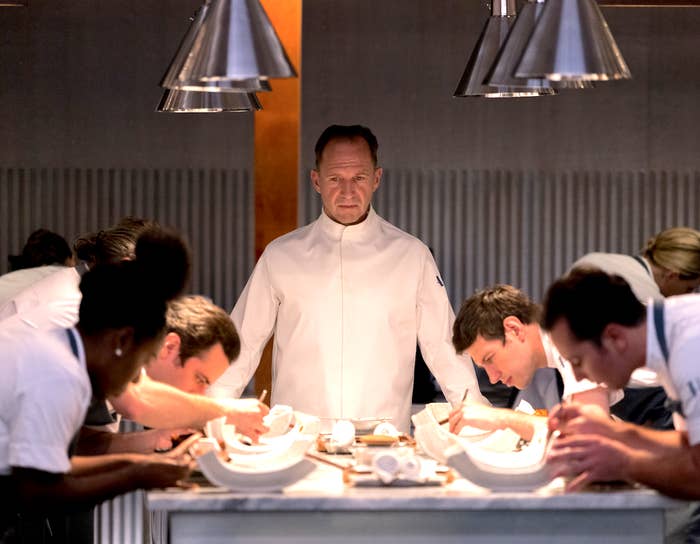 ralph fiennes looking at chefs plating in the menu