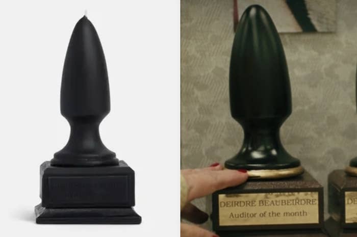 A large candle that&#x27;s shaped like a butt plug, and the same shape award from the movie with a plaque that reads deirdre beaubeirdre auditor of the month