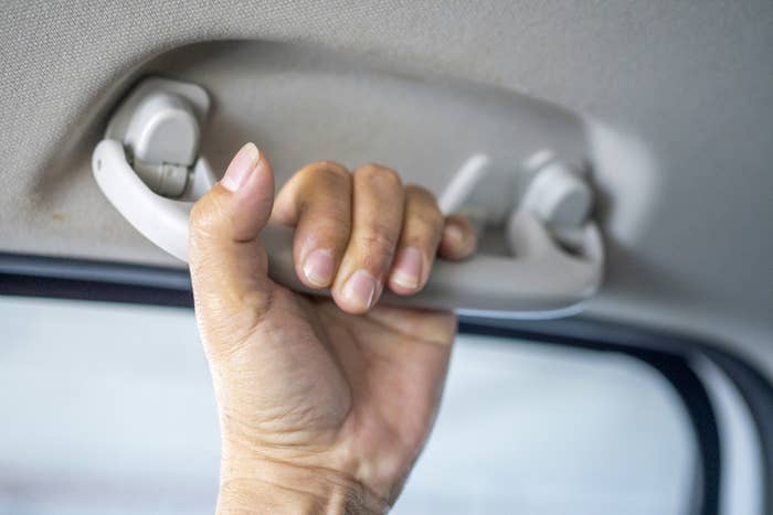 hand holding the handle above the window in the car