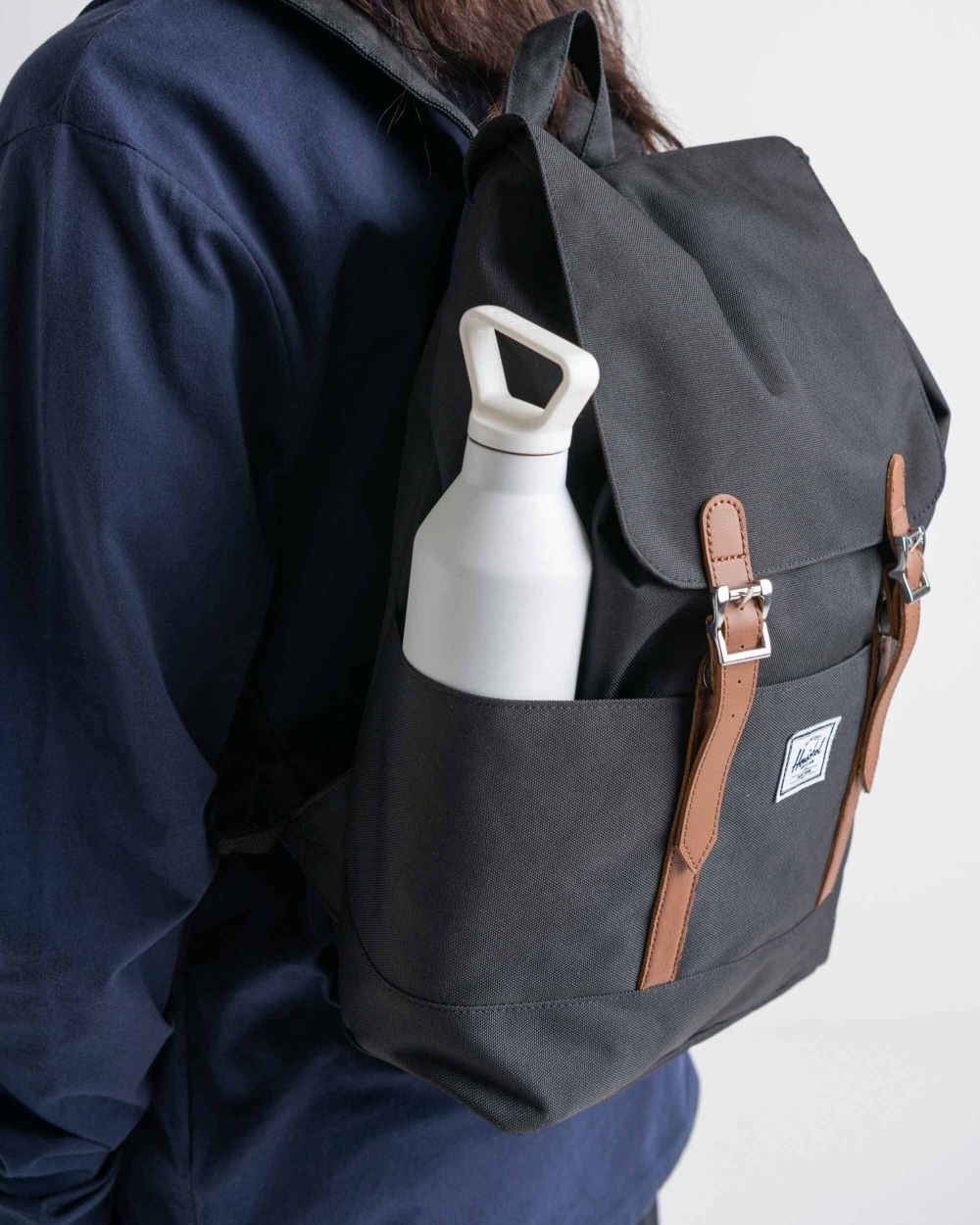 The black backpack with water bottle pocket and brown straps