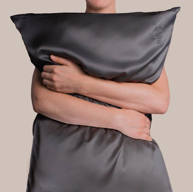 a model hugging a charcoal colored pillow case