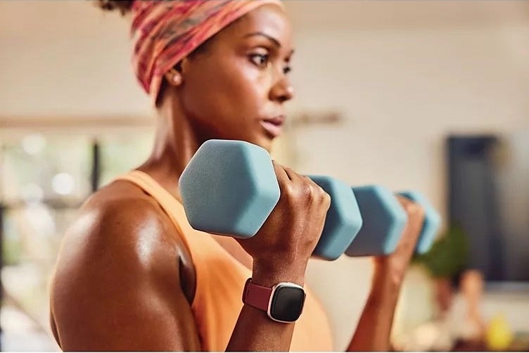 Someone holding two weights while wearing the smart watch