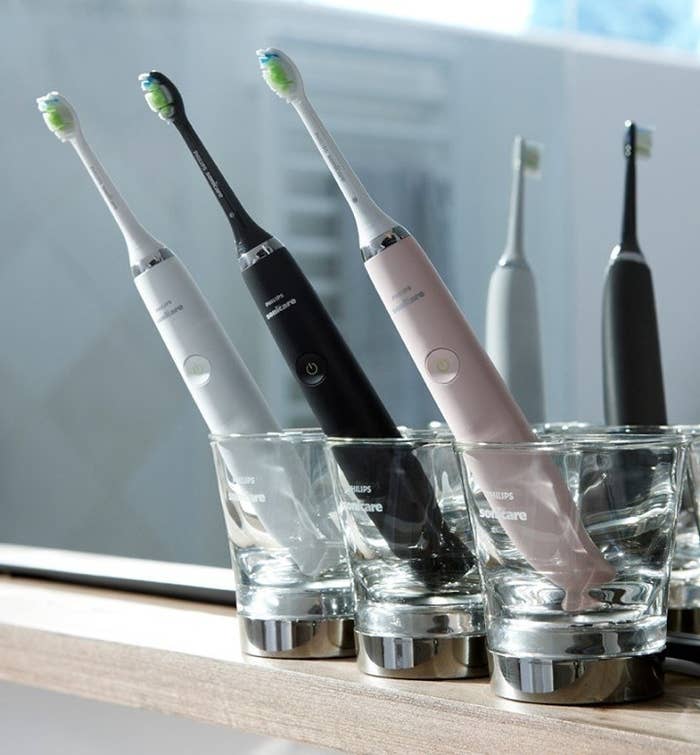 a trio of philips toothbrushes in their charging glasses